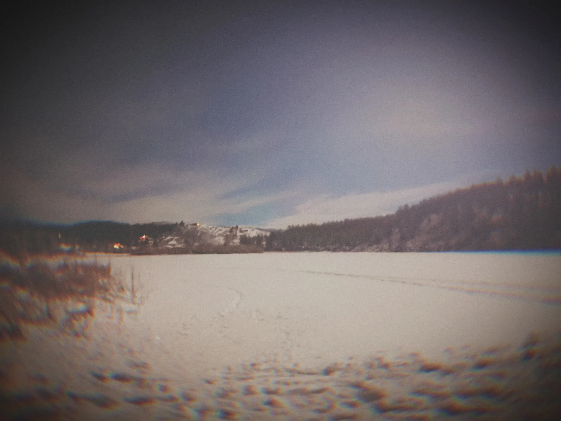 Atmospheric frozen lake landscape with a moody dark sky and distant treeline